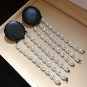 Detailed view of vintage-style black wooden earrings with elegant long white pearl tassels