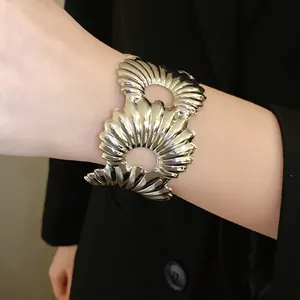 Nahaufnahme eines silbernen Manschettenarmbands mit wellenförmiger Muschelstruktur