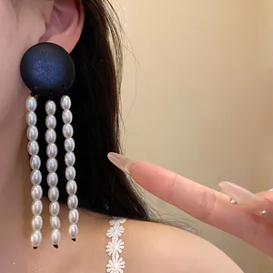 Close-up of vintage black wood and pearl tassel earring worn on an ear for detail