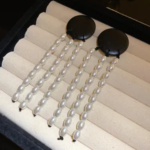 Close-up of vintage black wood earrings with white pearl tassels on a display tray.