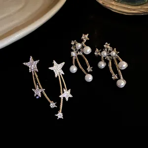 Vista macro di eleganti orecchini a stella con strass pavé e perle su sfondo nero lucido