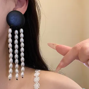 Detailed close-up of vintage black wood and white pearl tassel earrings on model