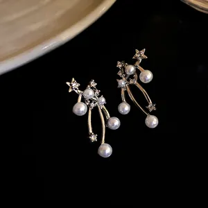 Orecchini eleganti a lobo con stelle e perle e strass luccicanti su fondo scuro.