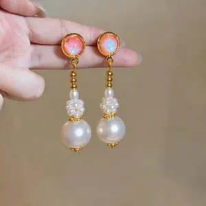 Close-up of elegant French style drop earrings with iridescent beads and white pearls.