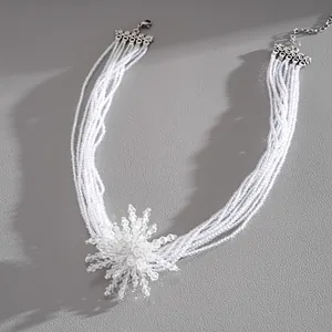 Close-up detail of multi-strand white crystal beaded necklace with starburst flower pendant
