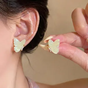 Elegant 18k gold plated resin butterfly stud earrings with sparkling zircons on model