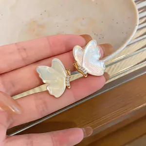 Detailed macro view of iridescent resin butterfly earrings with zircon accents and gold plating