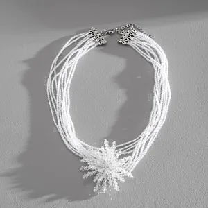 Close-up of multi-layer white crystal bead necklace with intricate flower pendant.