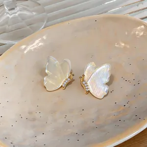 Close-up of elegant butterfly stud earrings with iridescent wings and gold plating