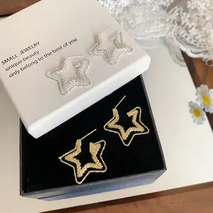 Primo piano di eleganti orecchini a stella a doppio strato oro e argento in scatola