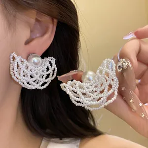 Detailed macro view of elegant white pearl beaded hollow-out stud earrings worn on ear.