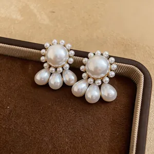 Close-up detail of silver needle pearl stud earrings with elegant teardrop pendants