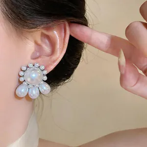 Detailed macro view of elegant pearl stud earrings with drop-shaped accents on model
