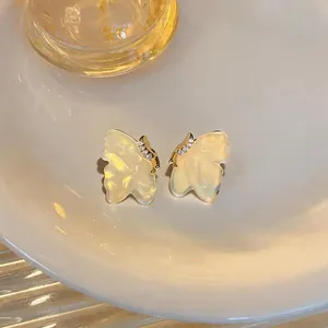 Close-up macro view of marbled resin butterfly stud earrings with sparkling zircon accents