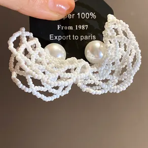 Detailed macro view of the intricate white bead mesh and luxury pearl stud earrings