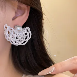 Detailed close-up of elegant pearl beaded hollow fan-shaped earrings worn by a model.