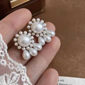 Detailed close-up showing the elegant round and teardrop pearl stud earrings in hand.