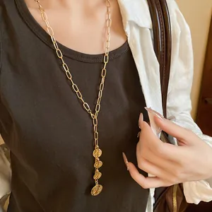 Detailed view of gold chain necklace with coin portrait pendants on a female model