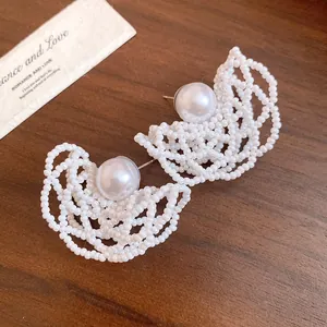 Close-up of white beaded hollow earrings with center pearl detail