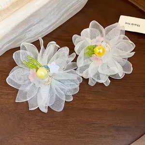Chiffon flower earrings with pearl center and green bead accents on wooden background