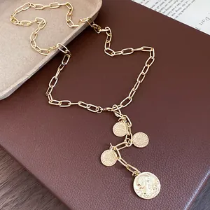 Gold metal chain necklace with multiple coin-shaped portrait pendants on brown leather base.