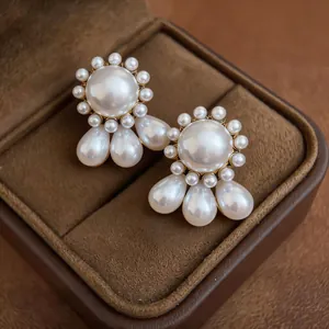 Detail showing elegant drop pearl earrings with teardrop pendants on a velvet box.