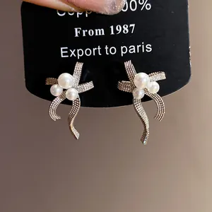 Elegant silver needle bowknot pearl earrings with white pearls on display card detail