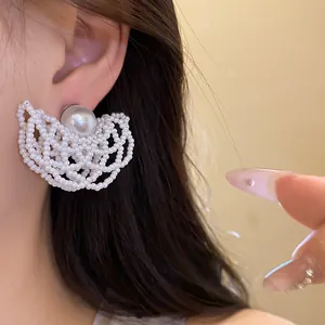 Detail of white pearl beaded hollow earrings with elegant silver needle design on ear