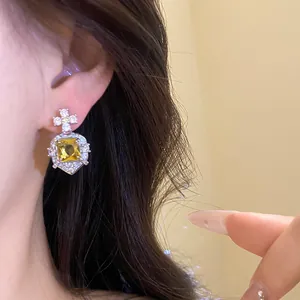 Detailed macro view of vintage square yellow zircon stud earring worn on model's ear