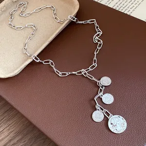 Detailed view of silver metal chain necklace with multiple round portrait coin charms