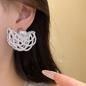 Close-up shot of elegant white pearl beaded openwork stud earring worn on ear for detail