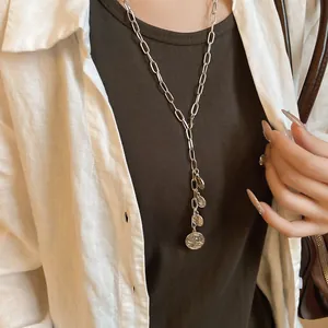 Macro detail of silver link chain necklace with multiple engraved coin pendants