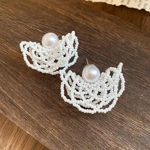Detailed view of white seed bead woven hollow earrings with central faux pearl stud