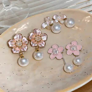 Macro detail of elegant cherry blossom pearl earrings with enamel and crystal accents.