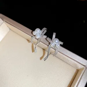 Close-up of elegant silver bowknot earrings with lustrous pearls and micro-pave crystals