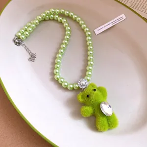 Detail view of a cute green plush bear pendant on a fashionable green faux pearl necklace