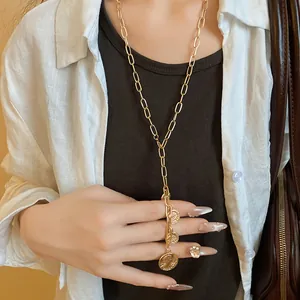 Detailed view of a gold Y-shaped chain necklace with three embossed coin pendants on a model