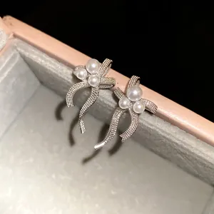 Close-up of elegant silver bow-knot stud earrings with pearl accents in a jewelry gift box.