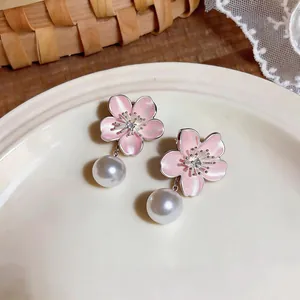 Exquisite detail of pink cherry blossom earrings featuring elegant white pearl drop pendants.