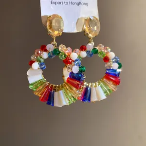 Detail view of colorful beaded hoop earrings with large champagne crystal studs