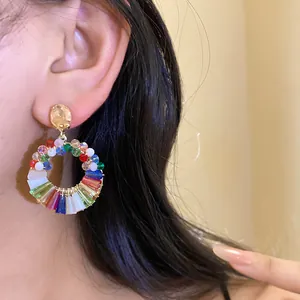 Close-up detail of stylish colorful crystal round hoop earrings worn by an Asian model