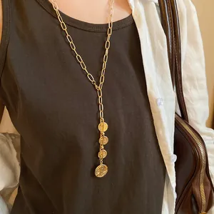 Close-up of gold chain necklace featuring multiple portrait coin pendants with tassel effect