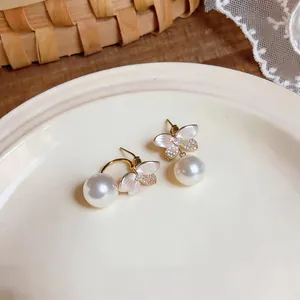 Detailed close-up view of butterfly pearl earrings with enamel petals and crystals