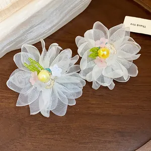 Close-up detail of elegant white chiffon flower earrings with central pearls and beads