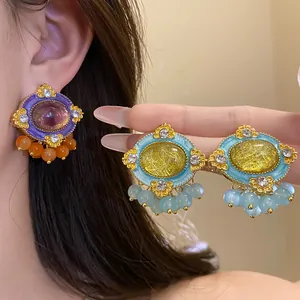Detail of vintage palace style oval resin stud earrings with rhinestones and beads.