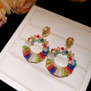 Close-up of colorful crystal round earrings on a white jewelry box.