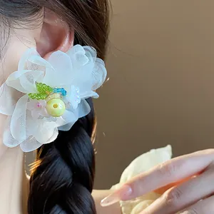 Detailed close-up view of elegant white chiffon flower earrings with beads on model