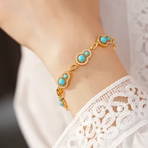 Close-up view of gold gourd bracelet with blue zircons and delicate white lace sleeve.