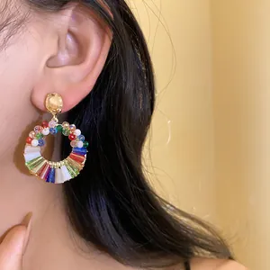Close-up view of colorful crystal hoop earrings worn on ear, showcasing vibrant beads.