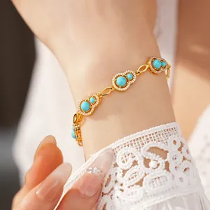 Close-up of gold gourd bracelet with blue stones and zircons on a white lace sleeve